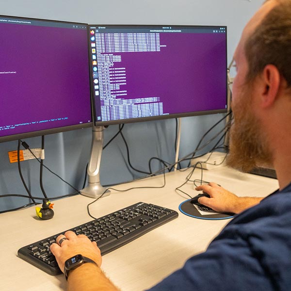 A photo of a person looking at two computer screens