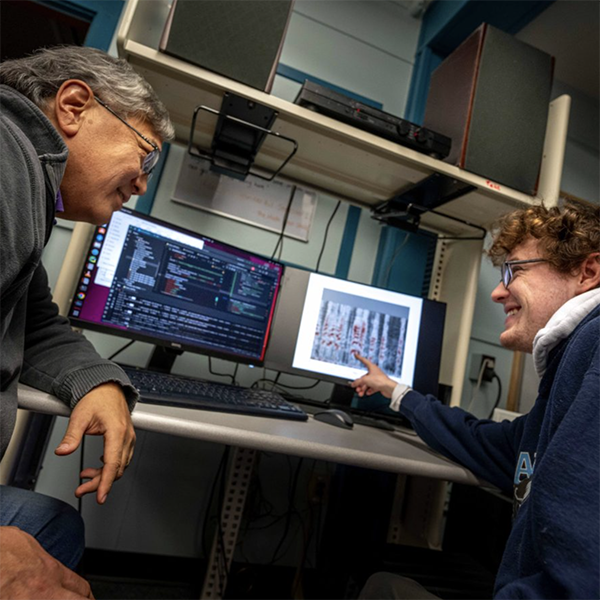 A photo of two people looking at a monitor